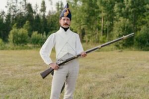 Man with Mustache Posing with Rifle During Historical Reenactment