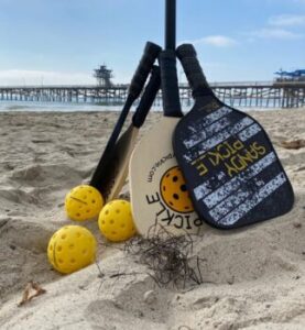 Sandy Pickle is played using a standard pickleball paddle and outdoor ball